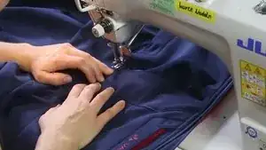 Den Flicken rundherum absteppen und beim Kreuzungspunkt beider Nähte die Naht durch Vor- und Zurücksteppen verriegeln.
