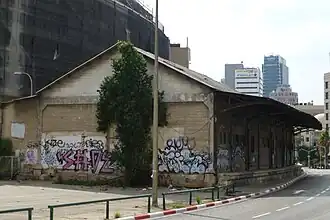 Blick 2014 aufs alte Zollamt mit Laderampe zu den Gleisen, jetzt Fahrbahn des Rechov haRakkevet, und Abbruchwand voller Graffiti, wo bis 1971 das Bahnhofsgebäude in gleicher Dimension anschloss