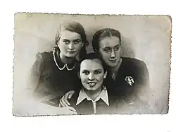 drei junge, gut gekleidete Frauen, die in die Kamera lächeln