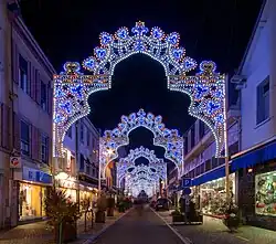 Fotografie. Die tor-ähnliche Weihnachtsbeleuchtung erscheint mit zunehmender Entfernung kleiner. Weihnachtsbeleuchtung in Montbéliard.