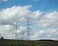 Links eine Hybridleitung: Unten eine 110-kV-Leitung in Donau-Anordnung, auf der obersten Traverse liegt eine Bahnstromleitung. Rechts: Tonnenmast 380&nbsp;kV.