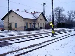 ein kleineres Bahnhofsgebäude am Rande eines verschneiten Bahnhofes mit schmalen Bahnsteigen