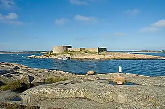 Foto einer kleinen Insel in einer Schärenlandschaft. Auf der Insel befinden sich die Grundmauern eines Forts.
