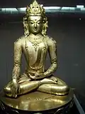 Eine goldfarbene Figur sitzt im Schneidersitz.