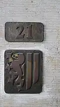 Zweiteilige Plakette für Dresden, mit der Hausnummer in einem Teil sowie dem Meißner Löwen und den Landsberger Pfählen aus dem Dresdner Stadtwappen im anderen Teil (vermutlich Messing- oder Bronzeguss)