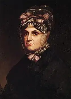 Anna Symmes, die Gattin von Harrison, trägt eine Haube und hat ihren Blick auf den Bildbetrachter fokussiert. Der Bildhintergrund ist sehr dunkel und lässt keine weitere Szenerie erkennen.