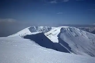 Blick vom Gipfelplateau des Geal-Chàrn über den Verbindungsgrat zum Aonach Beag, im Hintergrund der Beinn Eibhinn