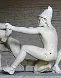Trojanischer Bogenschütze (der sogenannte Paris), Westgiebelgruppe des Aphaiatempels, ca. 505 bis 500 v.&nbsp;C. Die Ohrenlaschen sind hinter dem Kopf verschlungen.