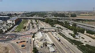 Luftbild 2020 mit Bahnhof Aschdod – ʿAd Halom (vorn), Anschlussstelle gleichen Namens, BIG Fashion vor Busdepot und Park ʿAd Halom (obere Mitte rechts) am Nachal Lachisch