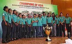 Cricketteam im Halbkreis hinter dem Pokal des Asia Cups