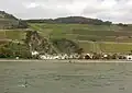 Assmannshausen im August 2016 von der linken Rheinstrecke gesehen. Der Ortsname ist am Rheinufer zu sehen.