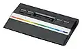 Vorderseite des Atari 2600 Junior (zweite Variante von 1986) mit Aufnahmeschacht für die Steckmodule und vier Bedienelementen