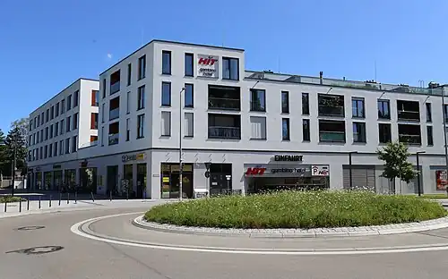 Gebäude vor der S-Bahn-Station mit Supermarkt (unten, Zugang links) und Hotel
