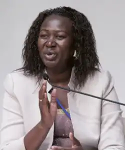 Awut Deng Acuil. Eine Frau mittleren Alters in einem weißen Kostüm.