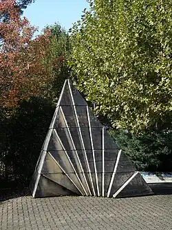 Owsky Kobalt (1937–2019). Bachmatten Schulhaus Reinach, Baselland. Steinplastik, Der Fächer, 1978. Höhe 3&nbsp;m, Grundkantenlänge 3,70&nbsp;m, 62 einzelne Steinböcke. Wettbewerb Kunstkredit Basel-Stadt. Architekten: Mariani und Meury, Reinach.