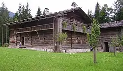 „Essglocke“ als Dach-/Glockenreiter: Eine überdachte Astgabel mit Glocke auf einem Bauernhof im Salzburger Land