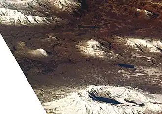 Der Belenkaja als schneebedeckter Kegel in der Mitte links (Aufnahme von Osten aus dem Space Shuttle)