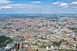 Vogelperspektive auf das Land Berlin, die drei Viertel der Farbfotografie einnimmt. Im unteren linken Bereich ist der Potsdamer Platz, in der Mitte des Fotos befindet sich der Fernsehturm und in der Ferne sind die ersten Felder und Wälder.