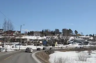 Foto einer Straße, die durch einen Ort führt. Die Landschaft ist verschneit.