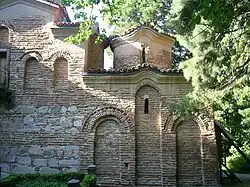 Ausschnitt der rechten Seite einer Mauer einer Kirche, die sichtbaren Steine und vermauerten Fenster sind terracottafarben