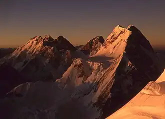 Blick vom K2 zu Gasherbrum-Gruppe und Broad Peak. Der Broad Peak Central ist der 2. Gipfel von rechts (ganz rechts der Hauptgipfel), seine Ostwand glänzt in der Morgensonne.