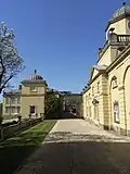 Links: Auffahrt von Castle Hill von unterhalb des Einfahrtsbogens mit Blickrichtung nach Westen zu den schmiedeeisernen Ziertoren zum Innenhof; Flügel für Dienerschaft rechts. Rechts: Nordfassade und Haupthof, gesehen von westlich der Tore des Hofes vor dem Flügel für die Dienerschaft hinter diesem Flügel.