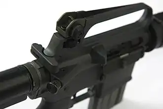 T-förmiger Spannschieber an einem Colt AR-15 Sporter Lightweight, rechts darunter die Schließhilfe