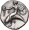 Didrachme. (ca. 415-390 v. Chr.), 21 mm. Delfinreiter nach l. In der r. Hand hält er einen Helm und in der l. Hand Schild und Speer. (Revers).[71]