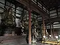 Inneres der ‚Großen Lehr-Halle‘ mit den fünf Meter hohen Statuen von Kongō-Satta (skr. Vajrasattva), Dainichi-Nyorai (skr. Maha-Vairocana) und Butchō-Sonshō (skr. Vijayosnisa)