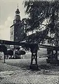Das Treffurter Rathaus in den 1920er Jahren (vor 1925) mit schieferverkleidetem Turm und der hölzernen Wasserleitung im Vordergrund, die aus der Quelle des Normannsteins 15 öffentliche Brunnen in Treffurt versorgte.