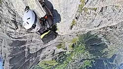 Kletterer am Daubenhorn im Leukerbad-Klettersteig am Aufstieg der Schlüsselstelle Via Konst in 2900 m Höhe, Blick herab auf das 1,4 km darunter gelegene Leukerbad