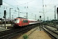 InterCity-Wagengarnitur im orientroten / pastellvioletten Farbschema mit Lok 103&nbsp;197 bei der Einfahrt in den Karlsruher Hauptbahnhof
