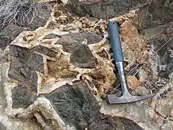 Große Titanitkristalle (schwarz) neben Diopsid (dunkelgrün) und Quarz (weiß) in einem Pegmatit (Radium Creek, South Australia)