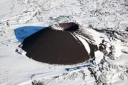 ein teilweise schneebedeckter, kegelförmiger Vulkan mit einem schalenförmigen Krater am Gipfel