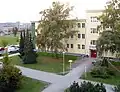 Blick aus dem 2. Stock des ehem. Stabsgebäudes 1 (Rückwärtige Dienste) auf das ehem. Transportbataillon. Linke Seite: heute Musikschule Joseph Schmidt. Rechte Seite mit ehem. Wohnheim: heute Beratungszentrum für in Not geratene Frauen und Bezirksamt Treptow-Köpenick. Foto von 2011.