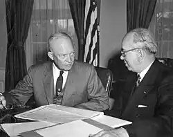 Schwarzweißfoto: Eisenhower und Strauss sitzen an einem Tisch, auf dem Akten ausgebreitet sind.