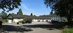 im Hintergrund die ein- bzw. zweigeschossigen Schulgebäude