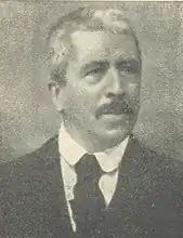 Ettore Ciccotti (vor 1939), mit Schnauzbart und bereits ergrauten Haaren, Portraitaufnahme in schwarzem Anzug, mit schwarzer Krawatte und weißem Hemd