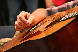 Haltung des Gitarrenplektrums beim Spiel einer Westerngitarre (m. Stahlsaiten)