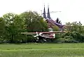 Das Motorflugzeug AVIAT HUSKY kurz D-ELMY bei der Landung. Im Hintergrund die zwei Kirchtürme der Schwanheimer Kirche.