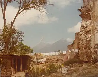 Hütte in den Ruinen eines spanischen Kolonialgebäudes in Antigua, mit dem Volcán de Fuego (links) und Acatenango (rechts) im Hintergrund.