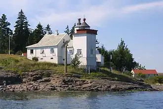 Foto eines weißen kleinen Leuchtturms, der sich direkt an der Küste befindet