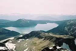 Ein kegelförmiger Berg ragt über einem alpinen See im Vordergrund auf
