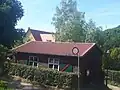 Baracke, die vor dem Bau des Gemeindezentrums (im Hintergrund) für Gottesdienste genutzt wurde