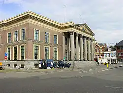 In der Mitte des Bildes ist der Gerichtshof in Leeuwarden zu sehen. Es ist ein älteres Gebäude mit einem Eingangsbereich gestützt von Säulen.