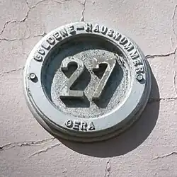 Runde Plakette für Gera mit Hausnummer (vermutlich Aluminiumguss).