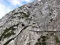 Höhleneingang im Gebirge und überdachter Wanderweg