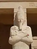 Hatschepsut mit Weißer Krone, Königsbart, Krummstab und Wedel, in die das Anch-Zeichen und das Was-Zepter eingearbeitet sind.
