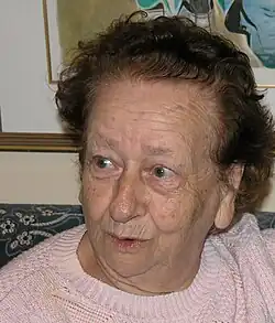 eine alte Frau mit wachen, lebhaften Augen und lockigem, dünn gewordenen Haar