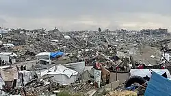 Inmitten einer Trümmerlandschaft hausen Menschen in Zelten